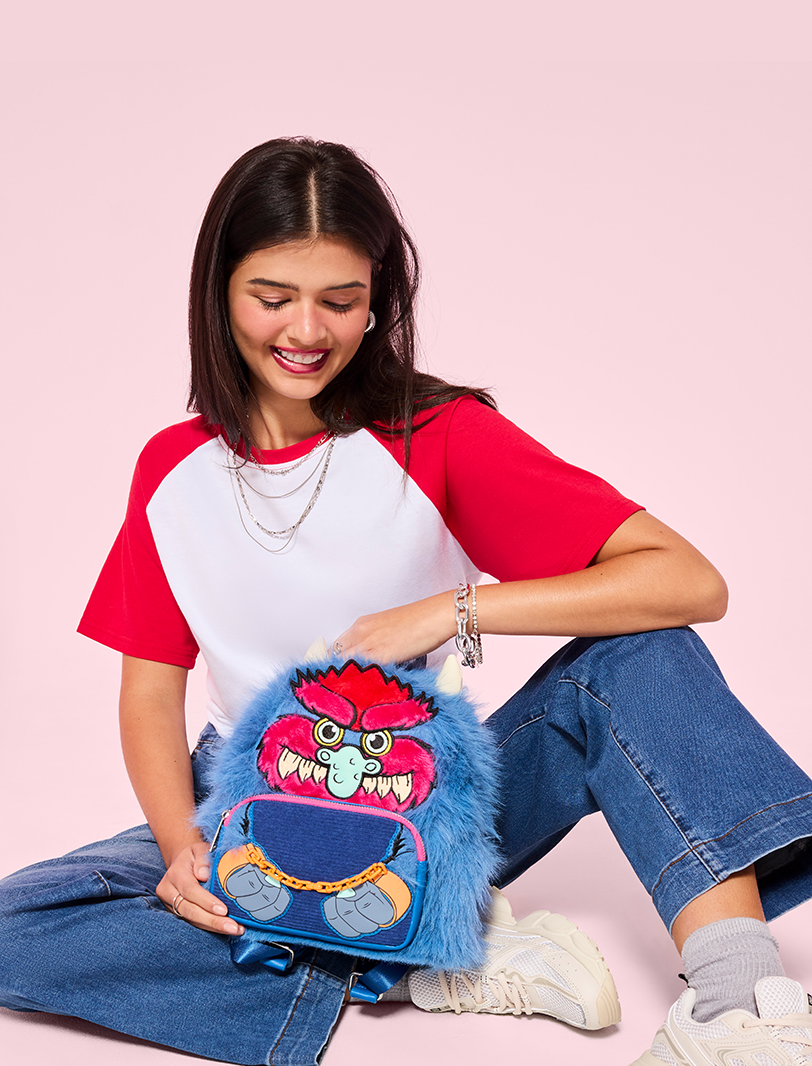 Model holding My Pet Monster backpack against a light pink background 