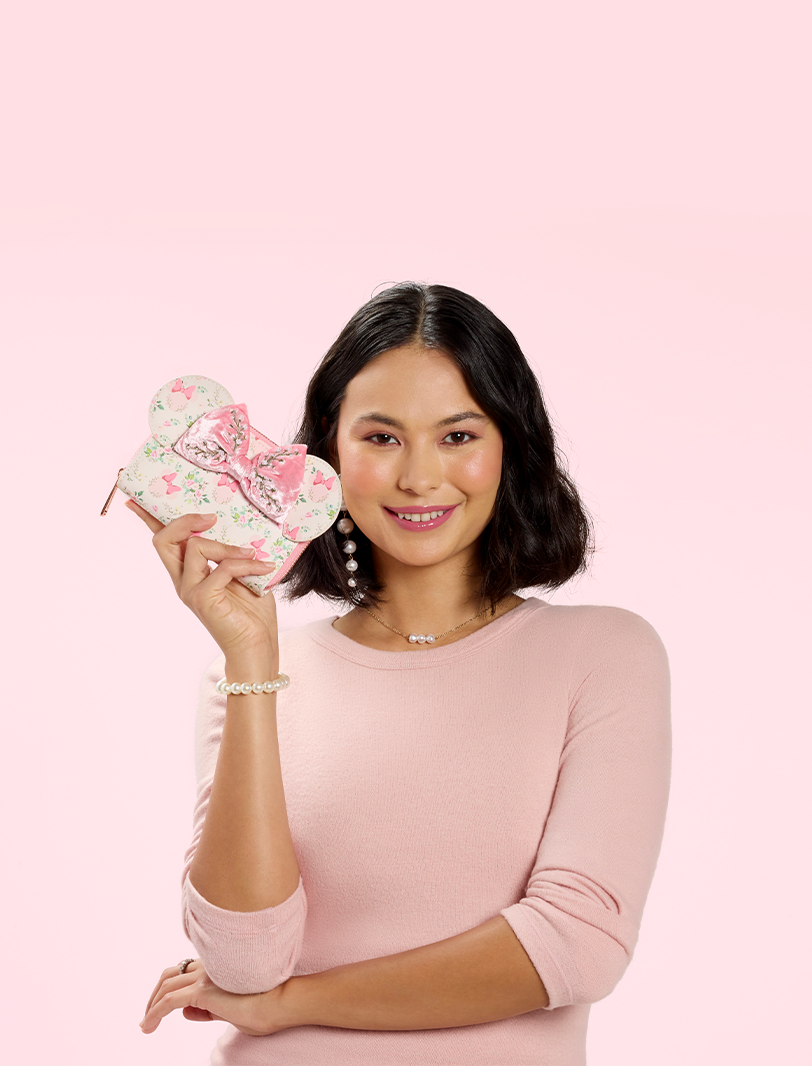 peach background with model holding Minnie Mouse wallet