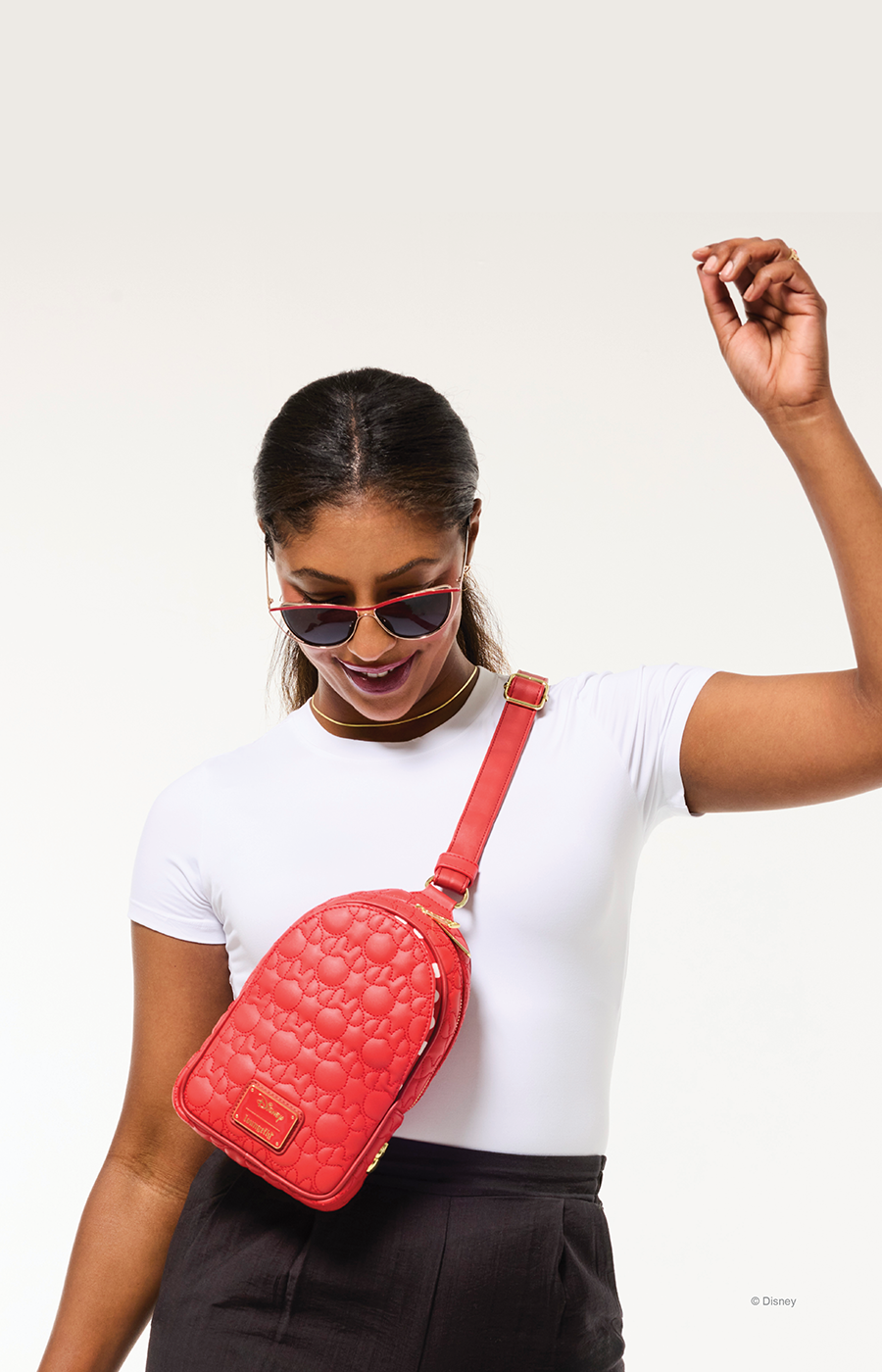 Model in plain white tee carrying a red, quilted Minnie Mouse crossbody around her body