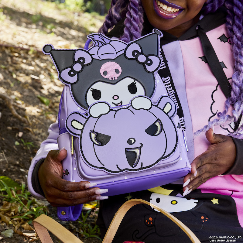 Woman sitting outside holding the purple Loungefly Sanrio Kuromi Pumpkin mini backpack, featuring Kuromi popping up from a purple jack-o'-lantern. 