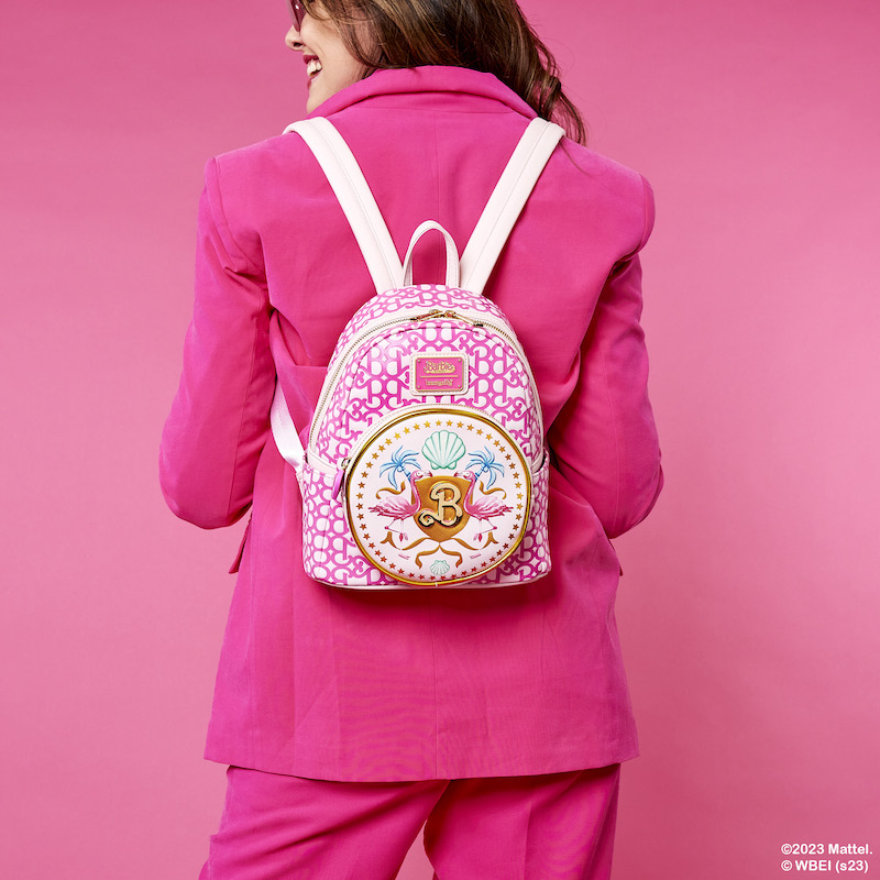 Image of a woman with her back turned to camera, wearing a pink suit, wearing the Barbie: The Movie mini backpack, against a pink background