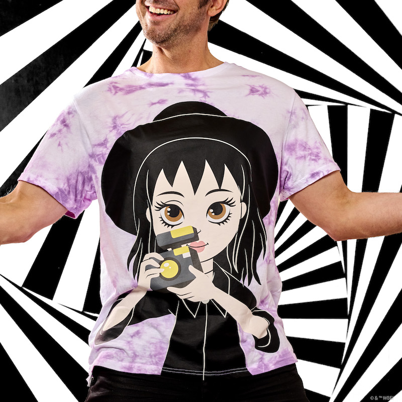 Man standing against a black and white background wearing the purple Tie-Dye Loungefly Beetlejuice Lydia Deetz Reversible Tee. The man wears the shirt with the image of Lydia Deetz with witch hat and camera facing the front. 