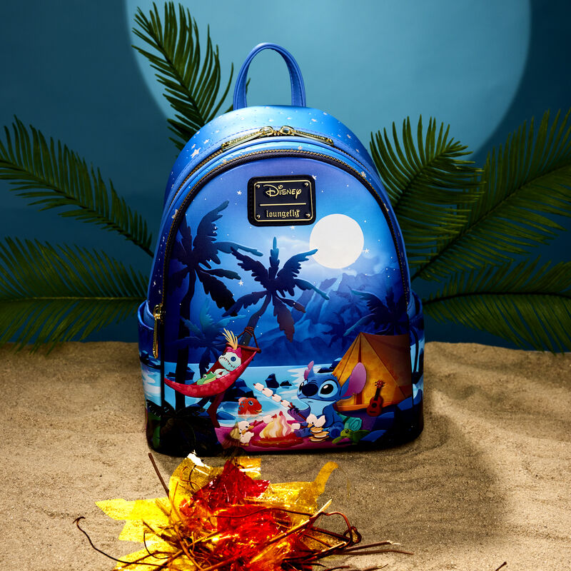 Blue Loungefly Stitch mini backpack featuring a camping scene on the beach with Stitch roasting marshmallows with Scrump in a hammock. The mini backpack sits in the sand on a beachy background.