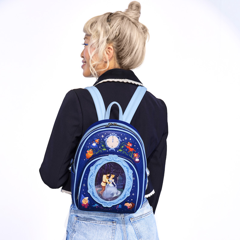 Woman facing away from camera and wearing the Loungefly Cinderella 75th Anniversary Royal Ball Mini Backpack, featuring Cinderella and Prince Charming dancing together surrounded by other characters from the movie.