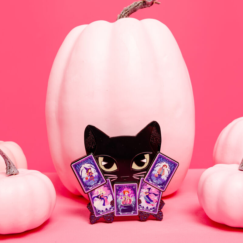 3" collector box Loungefly pin featuring Binx holding a set of tarot cards, featuring various characters from Hocus Pocus. It sits against a pink pumpkin and is surrounded by pink pumpkins against a pink background