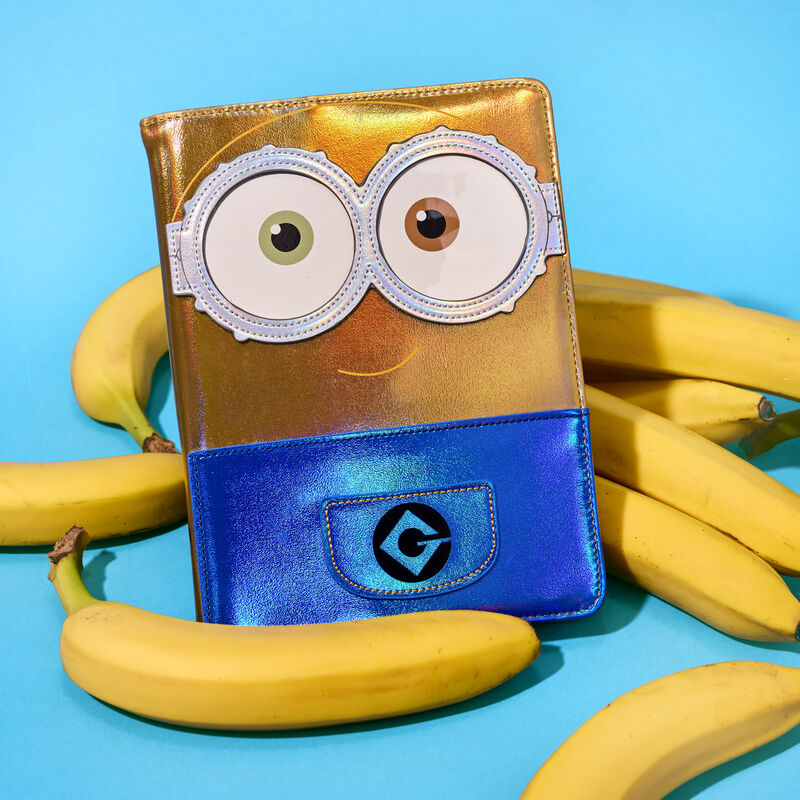 Refillable Loungefly Minions Bob Journal, featuring Bob in iridescent detail. The notebook sits on a pile of bananas against a blue background. 
