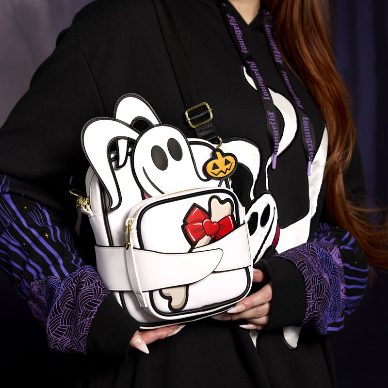 Close-up shot of a woman holding the Loungefly Zero Crossbuddies Crossbody Bag, featuring Zero in appliqué detail holding a removable and reversible coin pouch, featuring a bone with a bow on one side and a scary purple heart on the other.