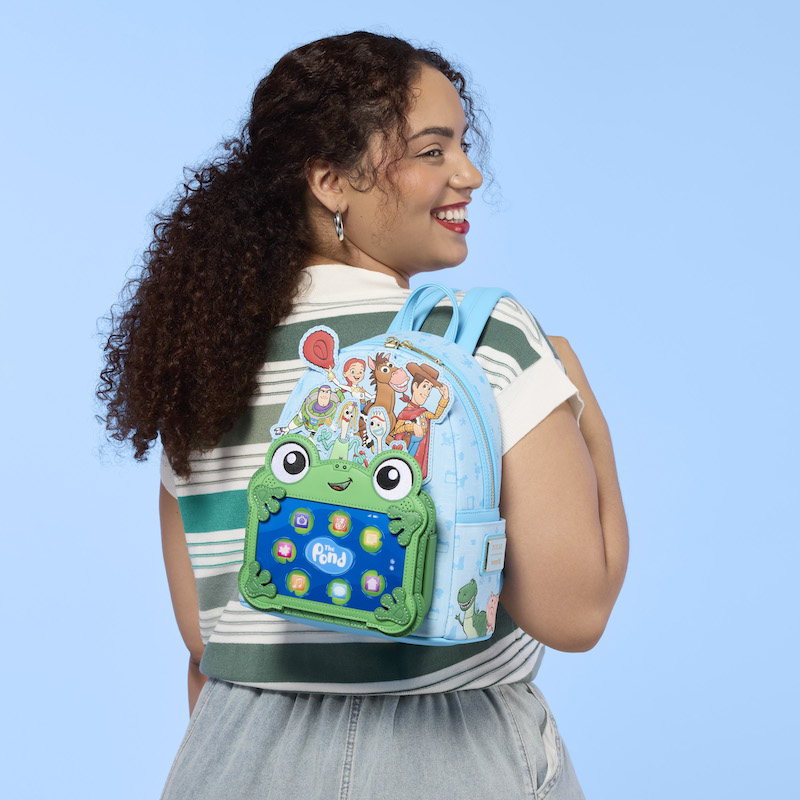 Woman facing away from camera, wearing a striped white-and-green top. She wears the Loungefly Pixar Toy Story 5 characters mini backpack over a shoulder. 