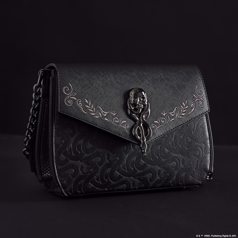 Black Loungefly Death Eater Crossbody bag featuring a metal clasp of the Dark Mark and debossed snake symbols. It sits against a dark background.