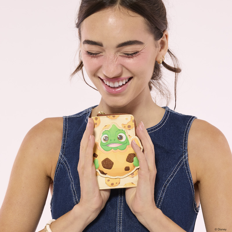 Woman smiling and laughing, holding the Loungefly Disney Tangled Pascal Cookie Card Holder 
