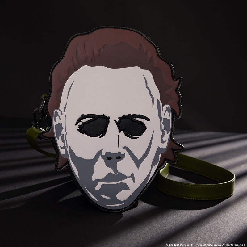 Loungefly crossbody bag featuring a large appliqué of Michael Myers in his mask. The bag sits against a dark background. 