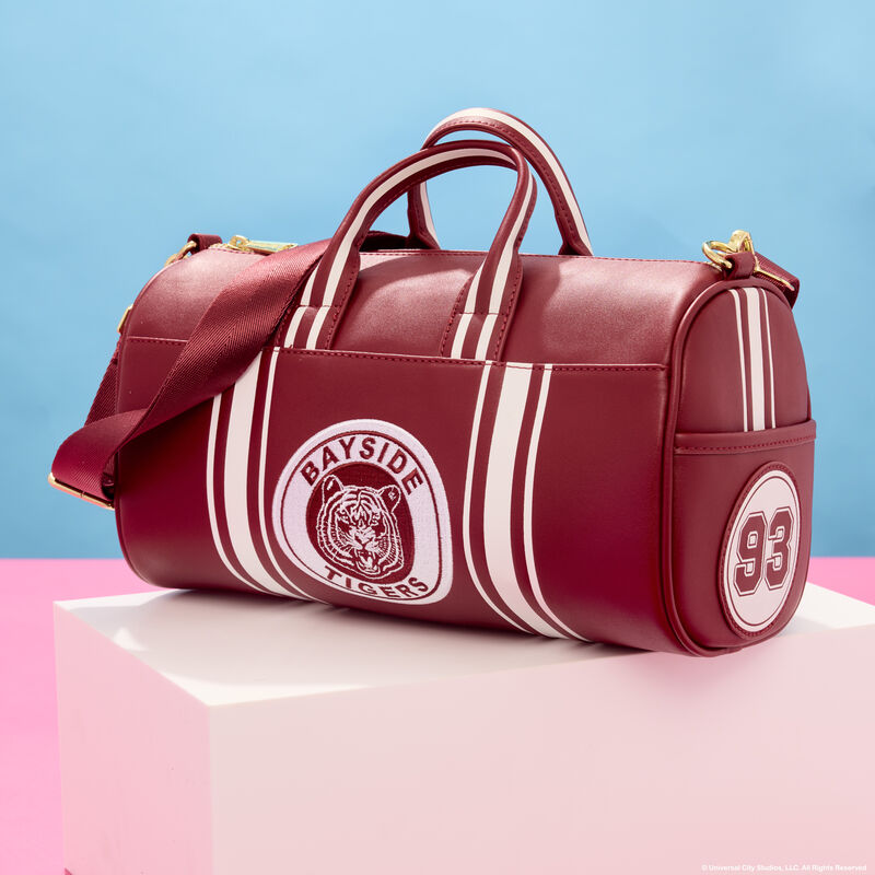 Loungefly Saved by the Bell Bayside High Tigers Duffle Bag that’s maroon and white. It sits on a white cube against a blue and pink background. 