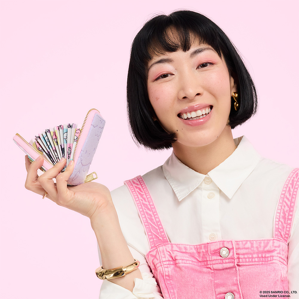 Pink background with model showcasing Loungefly San Diego Comic Con exclusive Sanrio My Melody & Kuromi Accordion Wallet