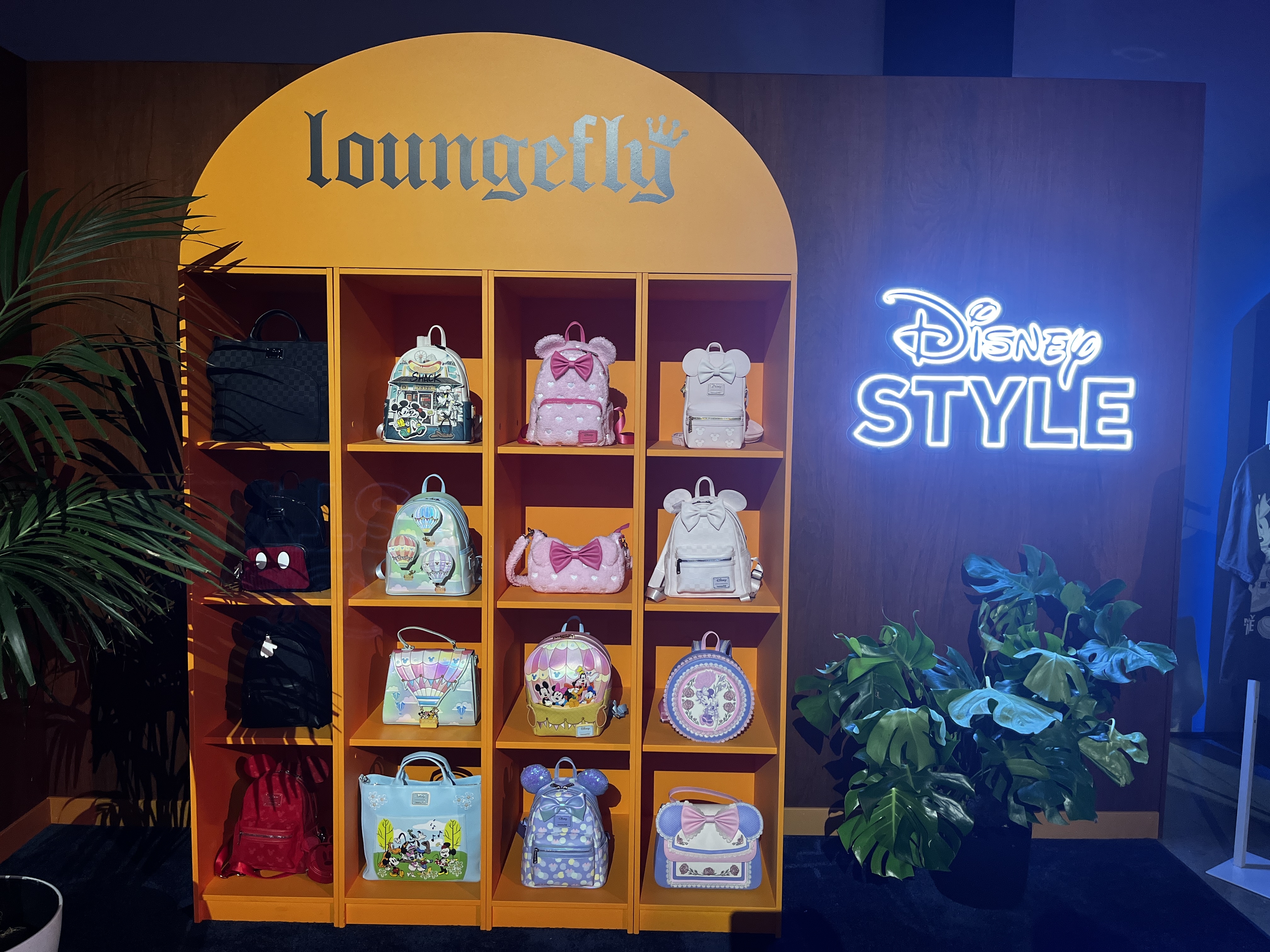 Image of Loungefly display of Disney bags next to a neon sign that says "Disney Style"
