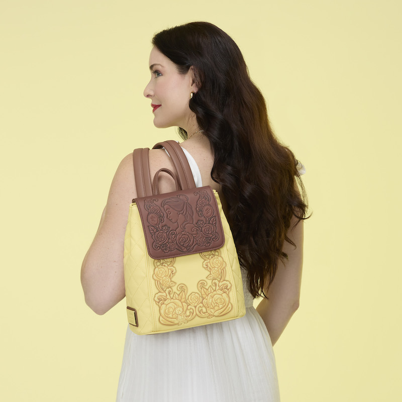 Woman facing away from camera, wearing a white dress and wearing the Loungefly Disney Beauty and the Beast Princess Belle Quilted Mini Backpack over a shoulder. 