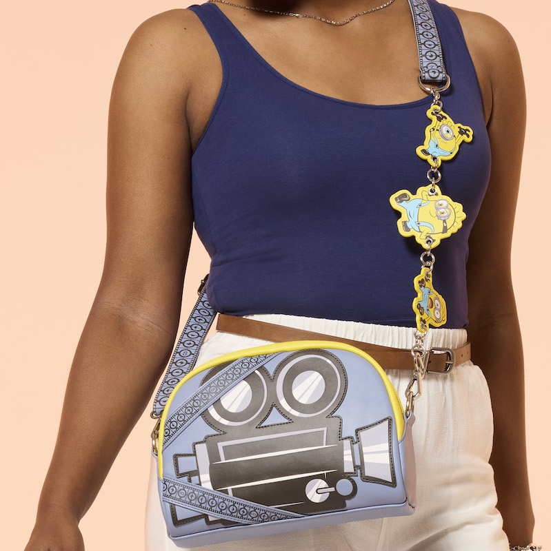 Woman wearing a blue top and white pants, wearing the Loungefly Minions and Monsters Crossbody Bag