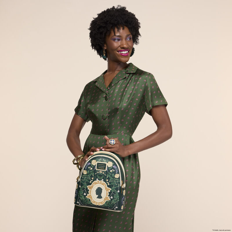Woman wearing a green silk dress and holding the Loungefly Bridgerton Silhouette Floral Mini Backpack. 