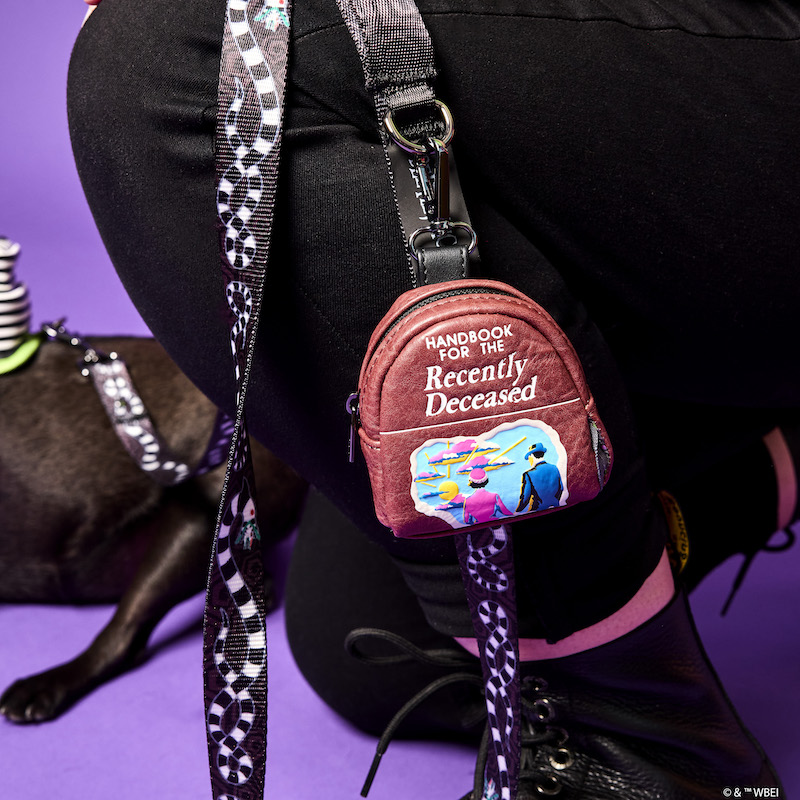 Image of person holding the Loungefly Beetlejuice Handbook for the Recently Deceased Treat & Disposable Bag Holder attached to the Beetlejuice leash.