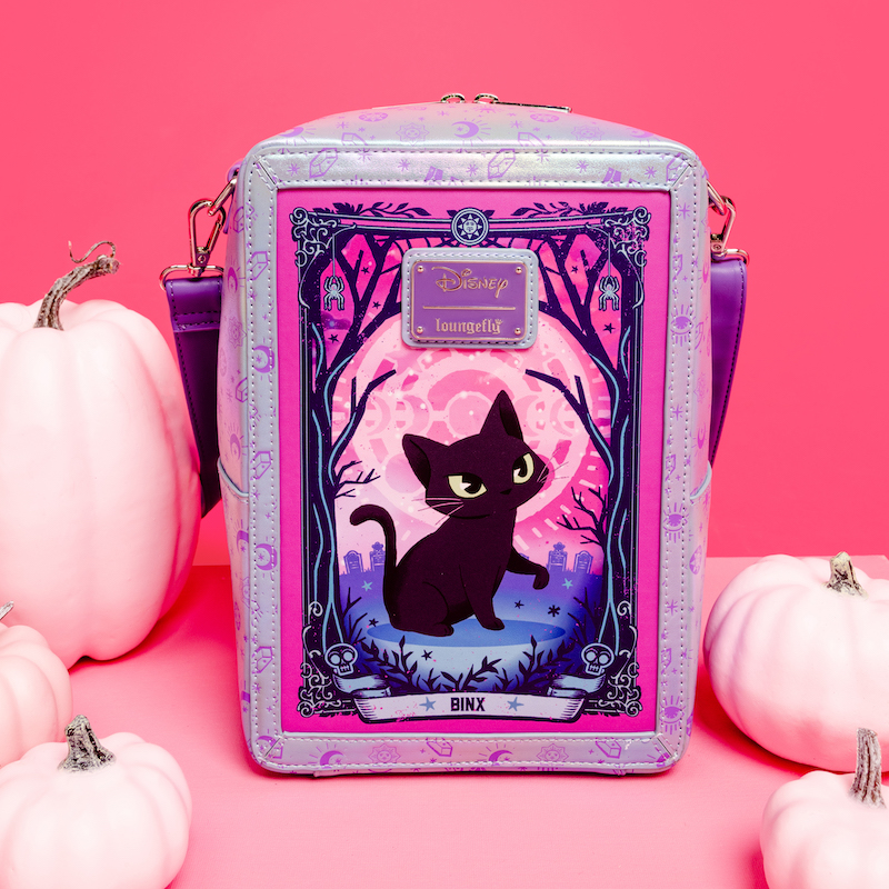 Back side of the rectangular Loungefly crossbody that looks like a tarot card. Binx is featured on the back of the bag in the forest. The bag sits against a pink background with pink pumpkins around it. 