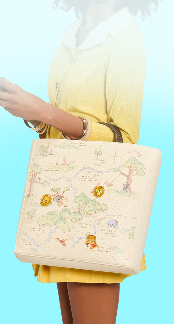 Light Blue background with model holding Loungefly Disney Winnie the Pooh Pin Trader Tote bag
