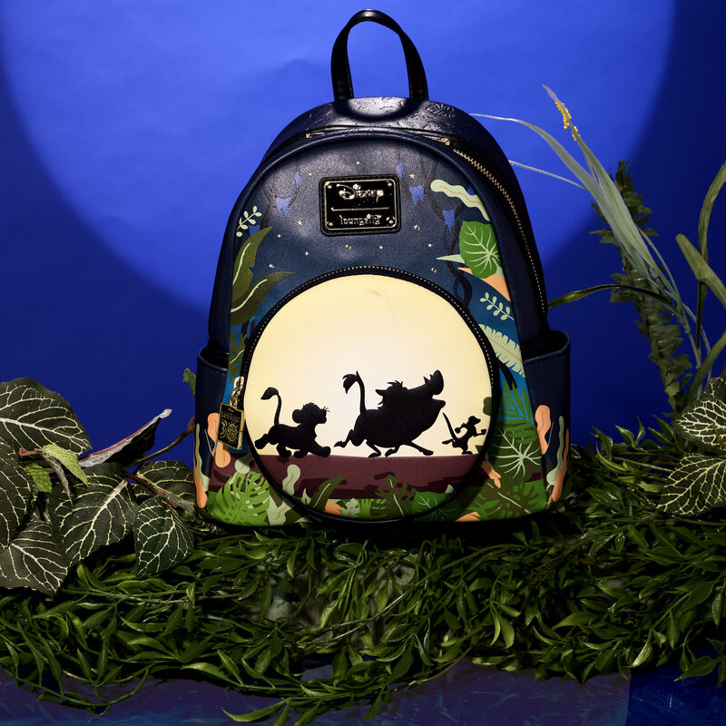 Loungefly The Lion King 30th Anniversary Hakuna Matata Silhouette mini backpack featuring Simba, Timon, and Pumbaa walking along a log against a full moon. The bag sits on green vegetation against a dark blue background. 