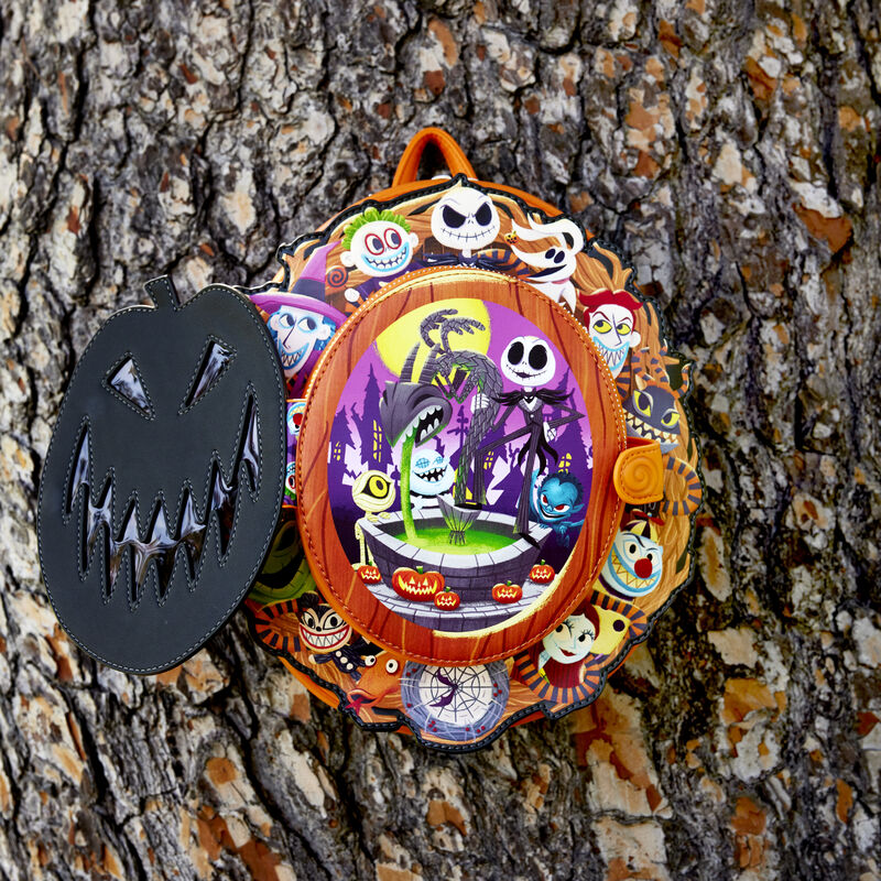 Image of the Nightmare Before Christmas Cameo Mini Backpack against a tree with the front flap open to show the scene behind the jack-o'-lantern face