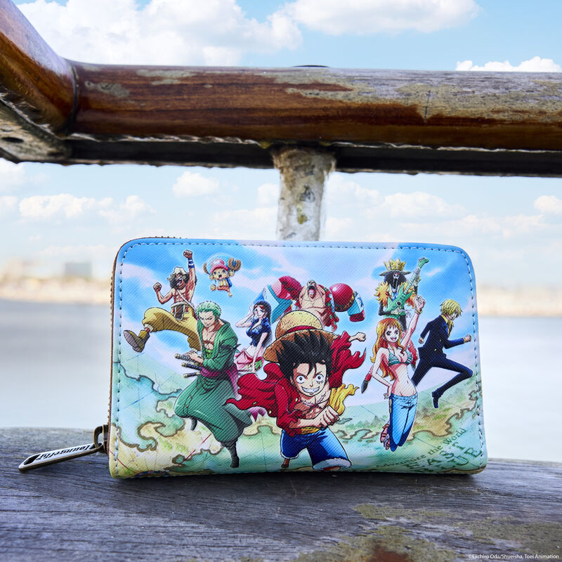 Loungefly One Piece wallet sitting on a dock by the water. The front of the wallet features Luffy, Chopper, Zero, Usopp, Robin, Brook, Nami, Sanji, and Franky in action. 