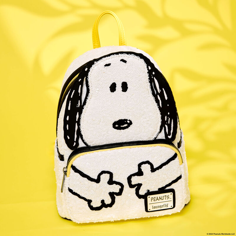 Limited Edition Loungefly Snoopy mini backpack covered in sequins. The bag sits against a golden yellow background. 