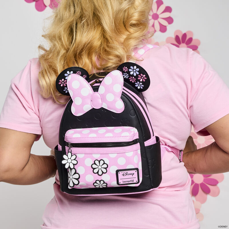 Blonde woman facing away from camera wearing a pink t-shirt and wearing the black and pink Loungefly Minnie Mouse Floral Rock the Dots Mini Backpack. 