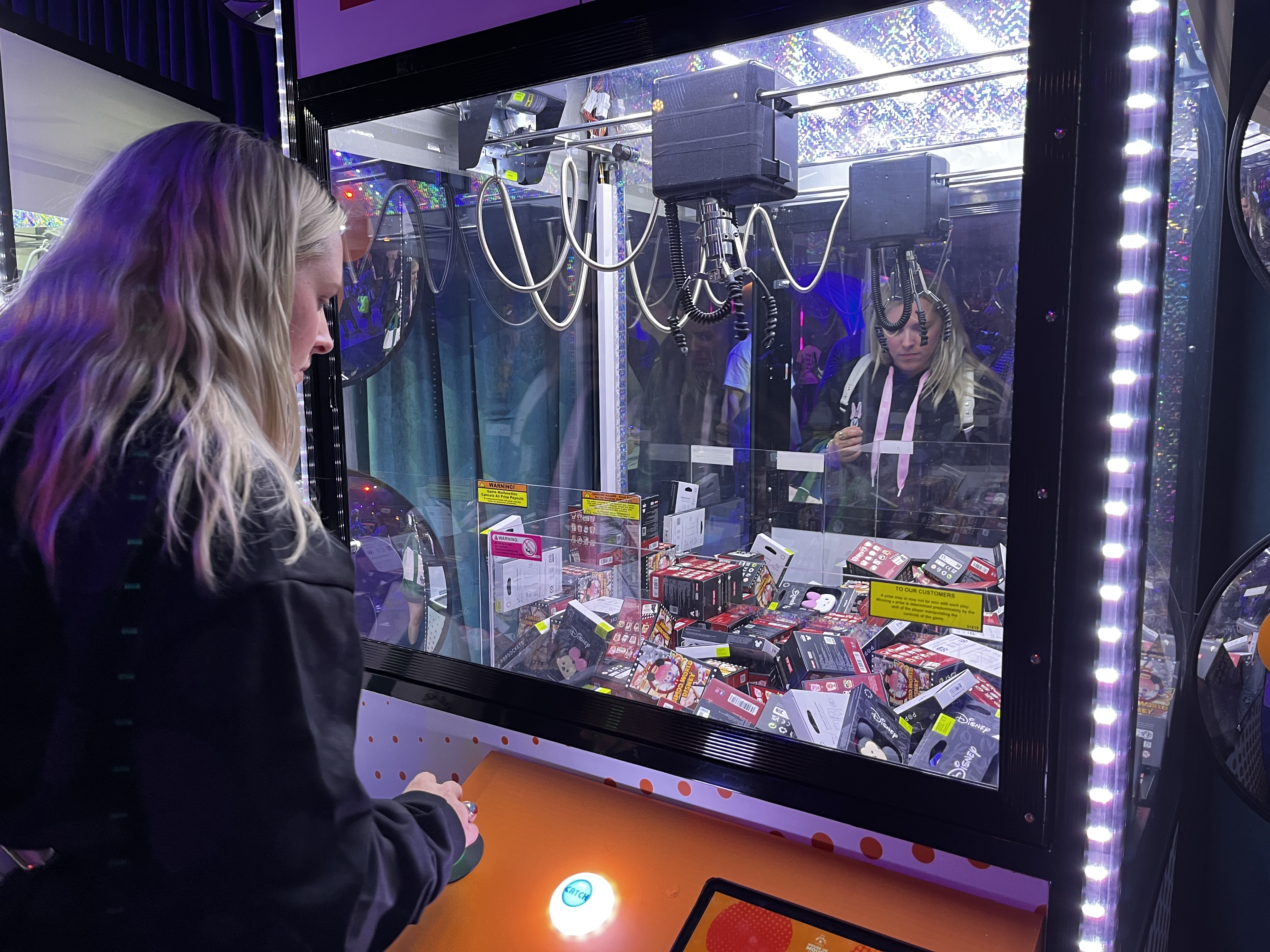 Woman concentrating as she plays a claw machine filled with pop sockets prizes