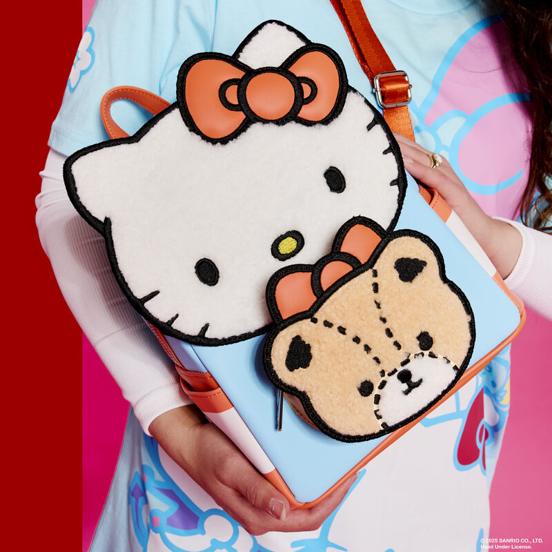 Close-up shot of a woman holding the Loungefly Sanrio Hello Kitty & Tiny Chum Sherpa Mini Backpack. The bag features Hello Kitty and Tiny Chum in appliqué detail covered in soft sherpa material. 