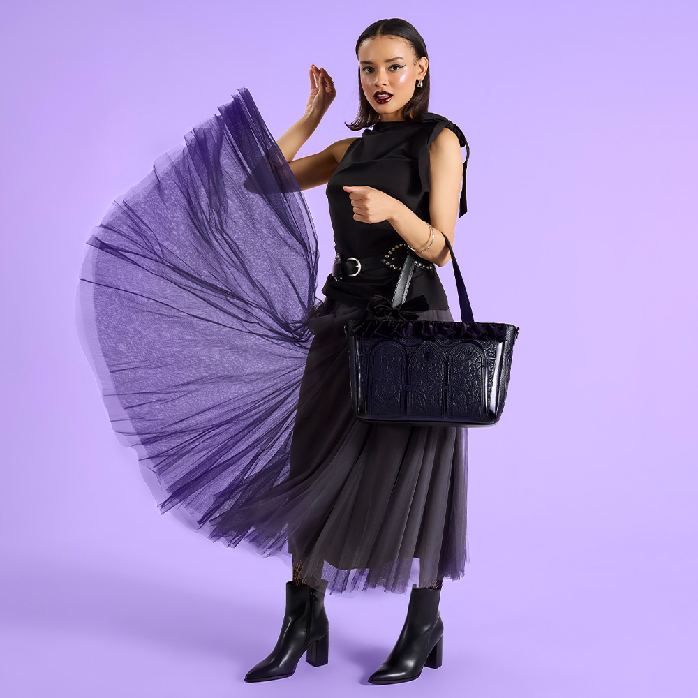 Purple background with model showcasing Loungefly August Disney Villains Stained-Glass Window tote bag