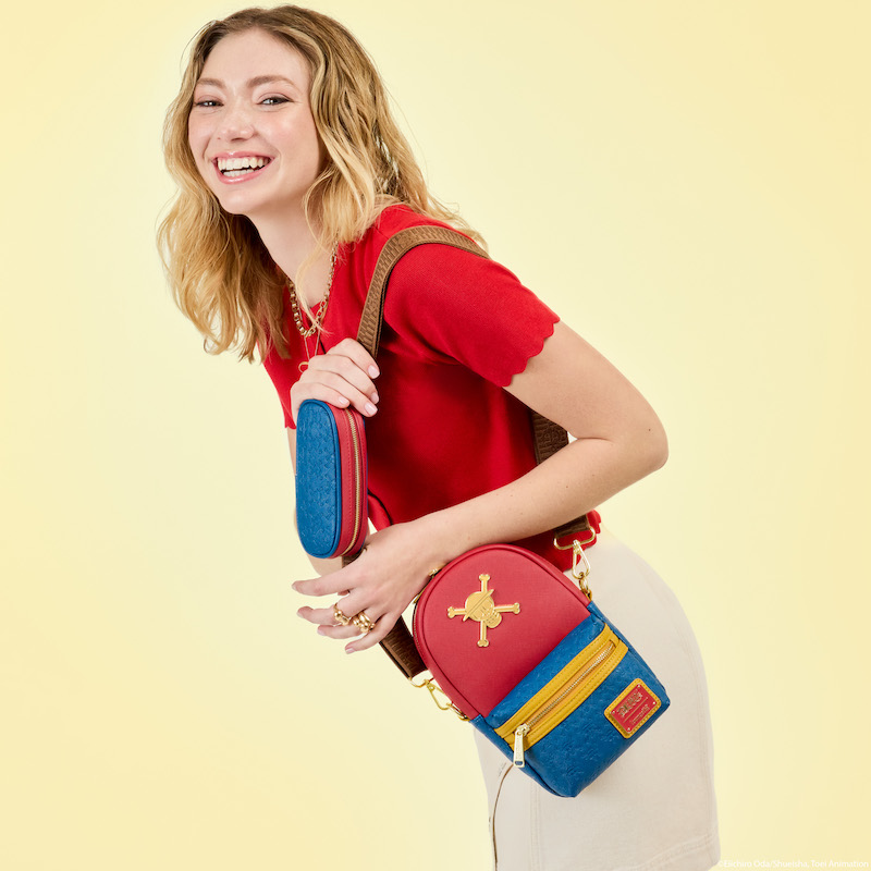 Woman facing sideways to camera and smiling, wearing a red top and white skirt and wearing the Loungefly One Piece Convertible Sling Bag over one shoulder. She stands against a yellow background. 