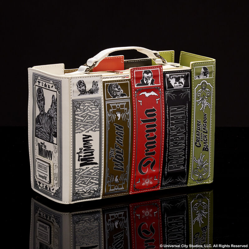 Crossbody bag featuring several books with titles of classic horror movies: The Mummy, The Wolfman, Frankenstein, and Creature from the Black Lagoon. The bag sits against a black mirrored background. 