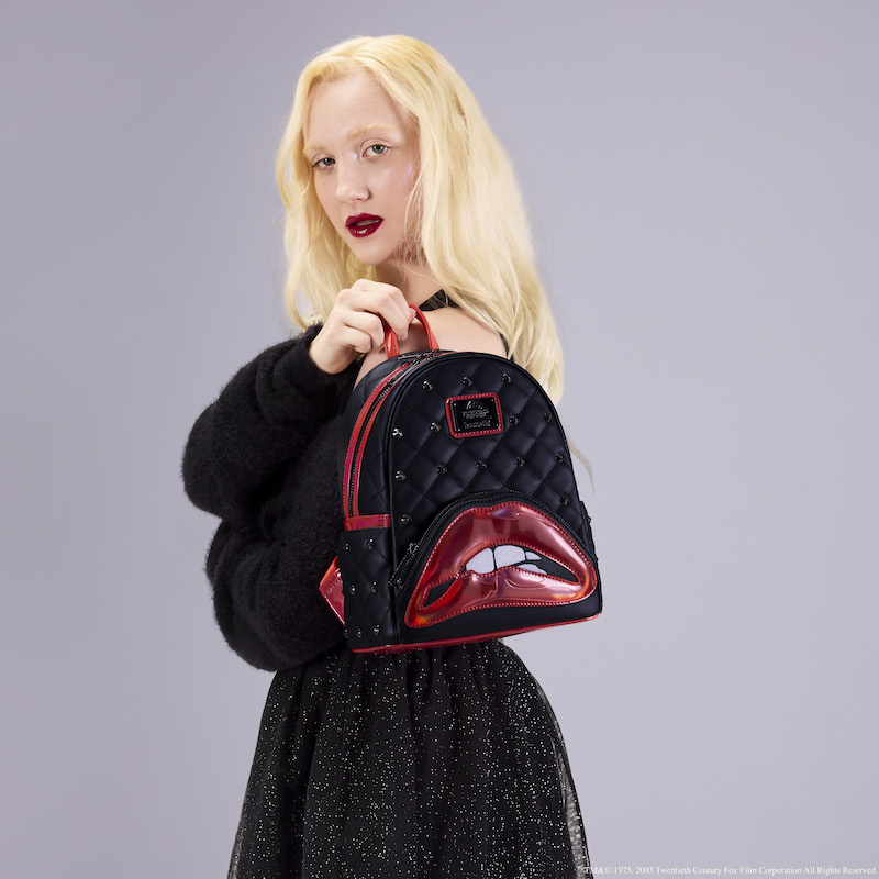Woman facing side to camera, looking over her shoulder at the camera holding the Loungefly Rocky Horror Picture Show mini backpack over a shoulder. 