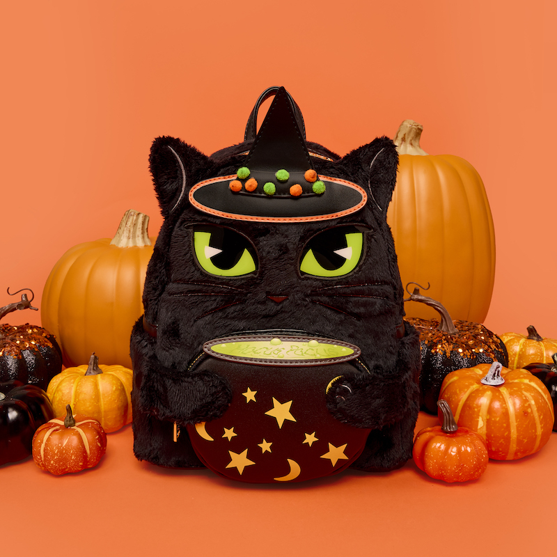 Black plush Loungefly Bins mini backpack featuring Binx holding a witch's cauldron and wearing a witch hat. His green eyes glow. The backpack sits against an orange background with black and orange pumpkins around it. 