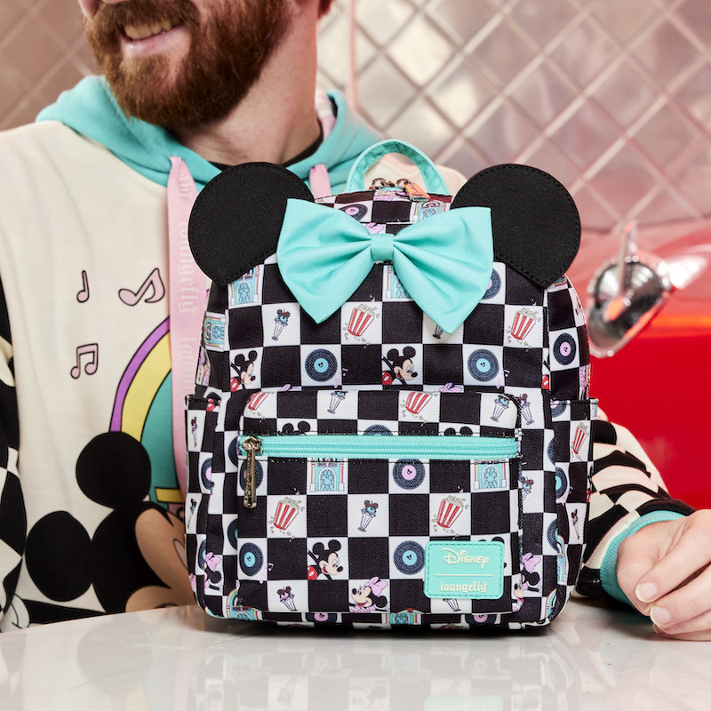 Man wearing the Date Night hoodie sitting at a diner table with the Mickey and Minnie Date Night Diner Checkered All-Over Print Nylon Mini Backpack sitting on the table in front of him
