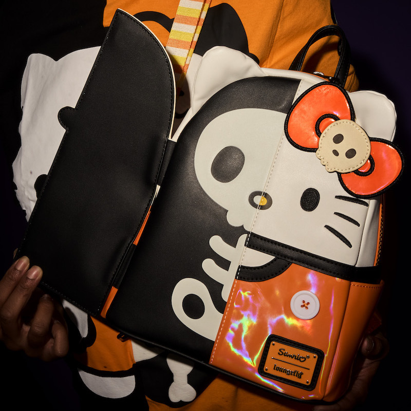 Someone wearing the Loungefly Hello Kitty Skeleton Mini Backpack, featuring Hello Kitty wearing holographic orange. One side of her opens as a flap to reveal her wearing a black skeleton suit. 