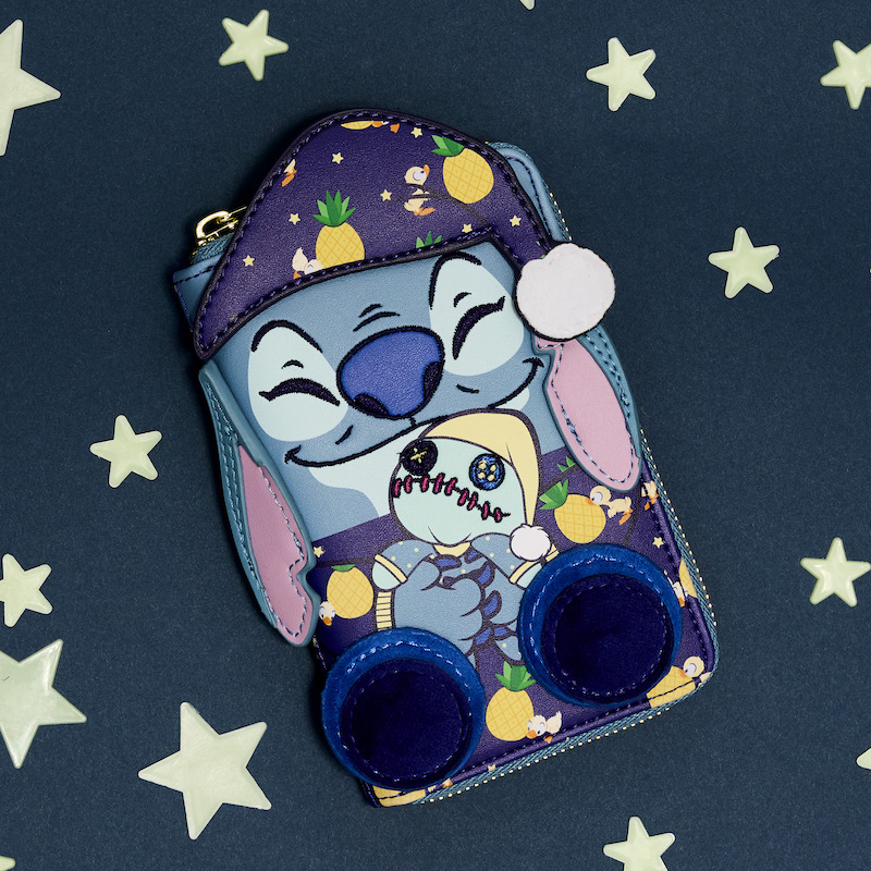 Zip around wallet featuring Stitch in pajamas cuddling Scrump. It lays against a dark blue background with glowing stars