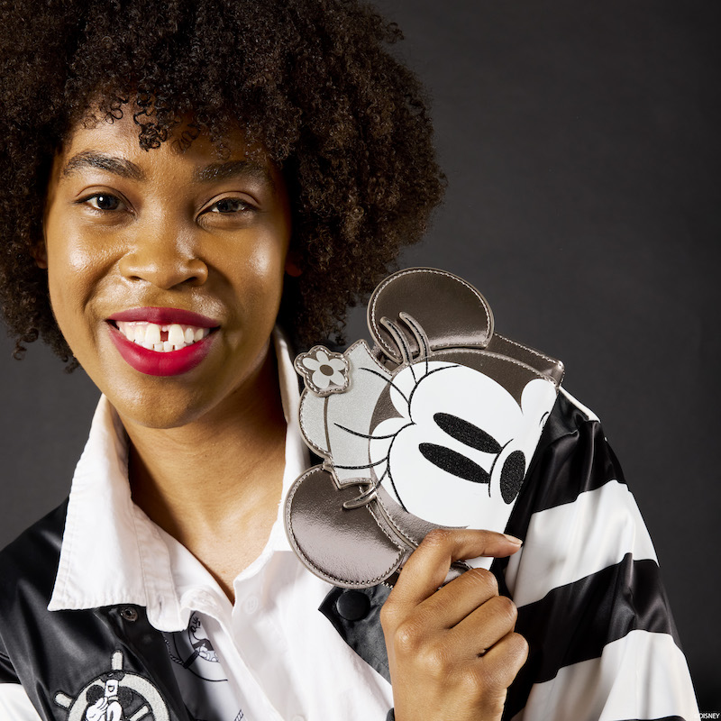 Woman smiling at the camera holding the Loungefly Disney Minnie Platinum Steamboat Willie Zip Around Wallet, featuring Minnie Mouse with 3D appliqué ears and hat. 