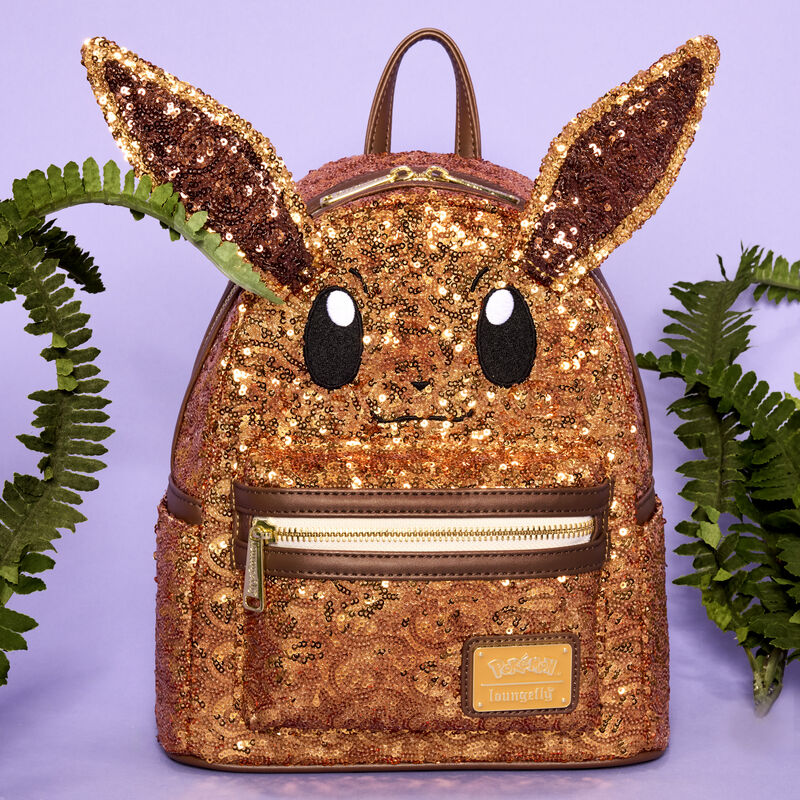 Loungefly Pokémon Eevee mini backpack covered in sequins. The bag sits against a purple background surrounded by some foliage. 