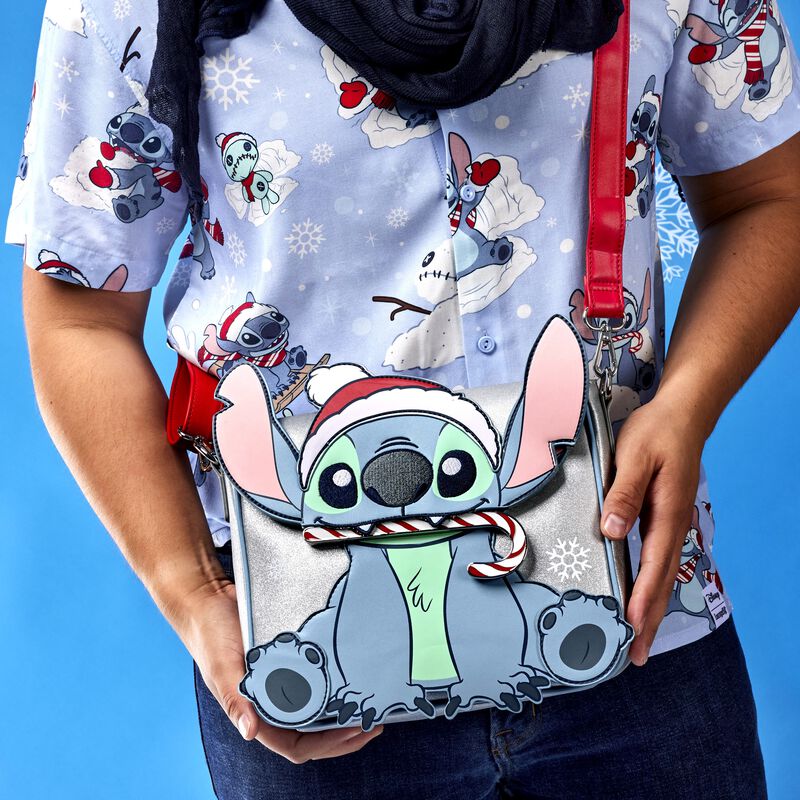 Image of our someone wearing our Stitch Holiday Glitter Crossbody Bag with the top flap closed, showing Stitch with a candy cane in his mouth