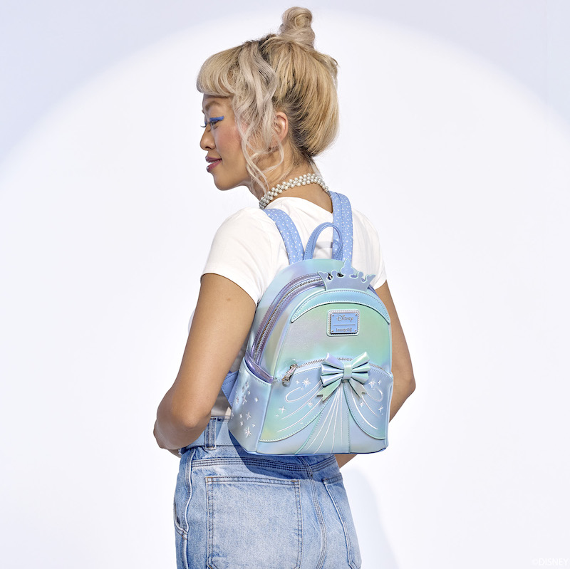 Blonde woman facing away from camera and wearing the blue iridescent Cinderella 75th Anniversary Shiny Series Mini Backpack. 