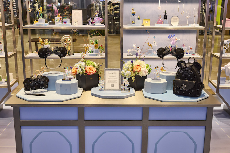Product display of the Loungefly Swarovski collection at the Swarovski store, featuring the mini backpack, wallet, and ear headband 