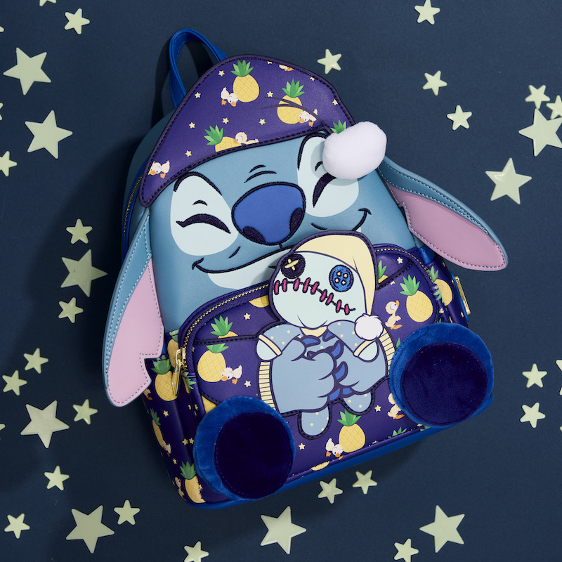 Mini backpack of Stitch wearing pajamas and cuddling scrump. the backpack lays against a dark blue background with glowing stars