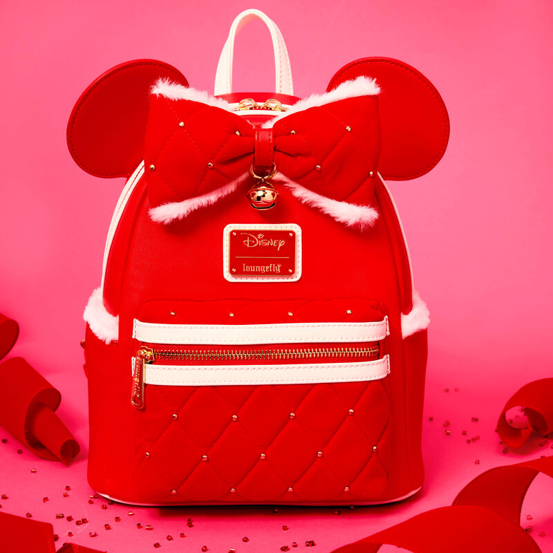 Red Loungefly mini backpack with a quilted design and white faux fur trim. It features 3D Minnie Mouse ears on it, too. It sits against a light red/pink background. 