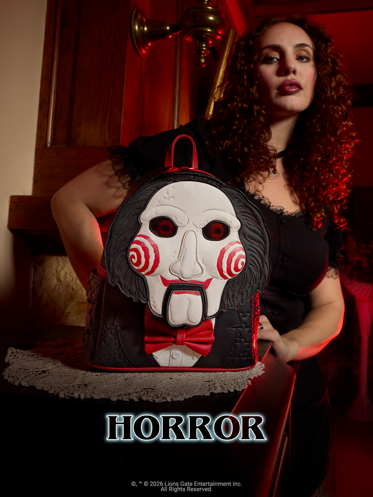 Dark, rustic house background with Red hues and model showcasing Loungefly Saw Billy the Puppet Mini Backpack