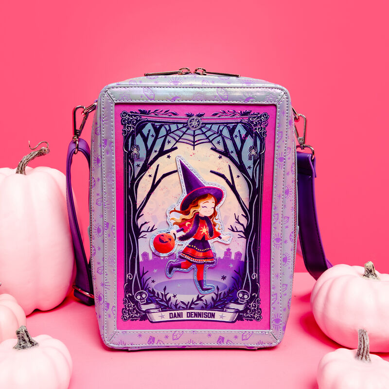 Rectangular Loungefly crossbody bag that looks like a tarot card with Deni Dennison walking through the woods in the center. The bag sits amongst pale pink pumpkins against a pink background. 