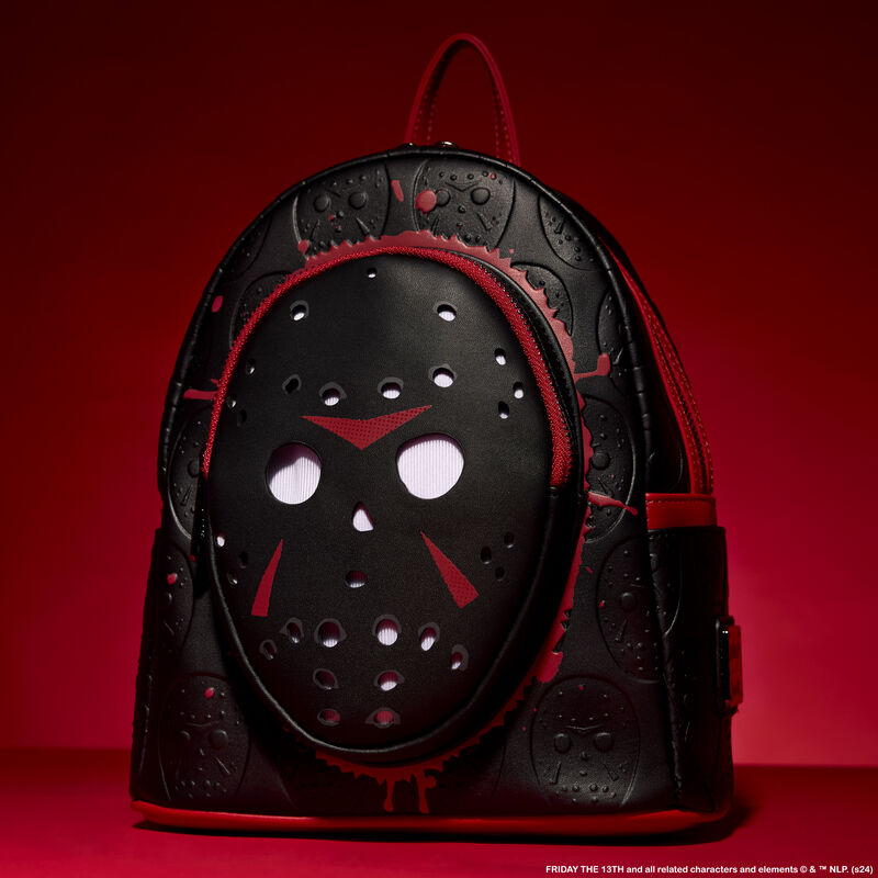 Black Loungefly mini backpack featuring Jason's mask from Friday the 13th. The bag sits against a red background. 