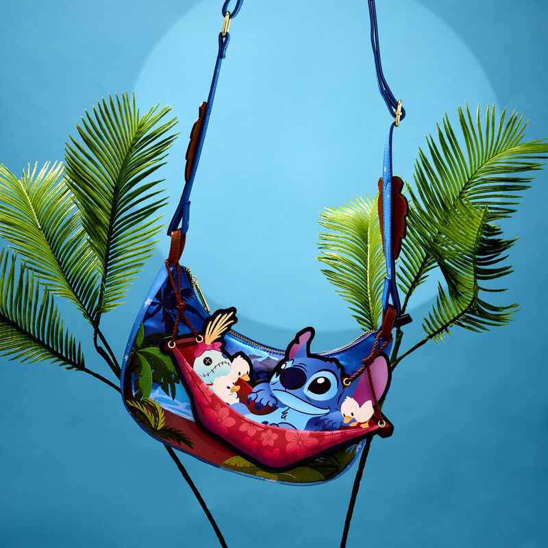 Crossbody bag featuring Stitch and Scrump swinging on an appliqué hammock. The bag hands in the hair between two thin trees against a blue background.